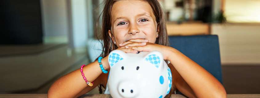 Young girl with hands resting on top of large white & blue patterned ceramic pig