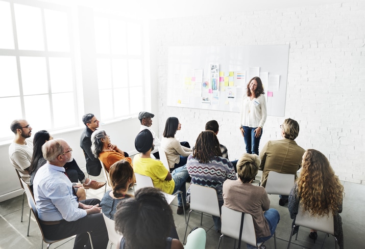 Woman presenting to a group of people sat on chairs facing her